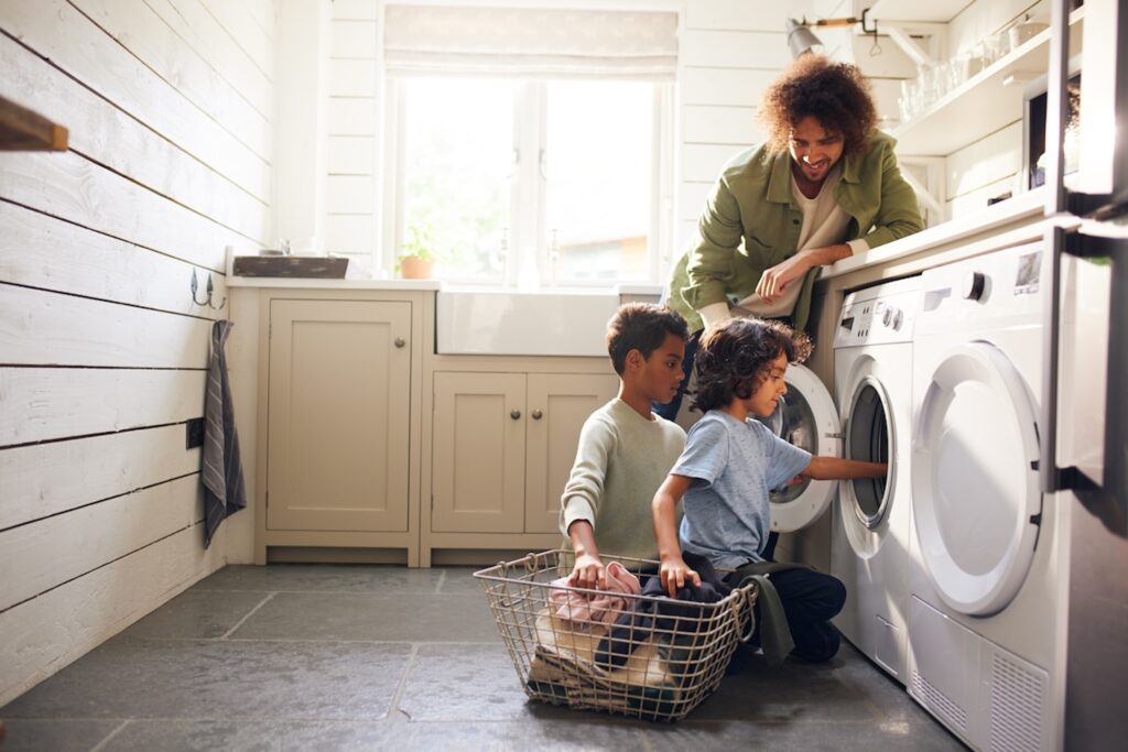Boys doing laundry with father watching
