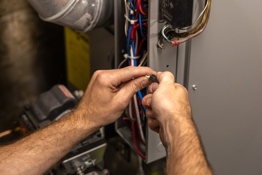 Electrician is connecting wires inside an electrical panel while installing a modern heating system. Selective focus