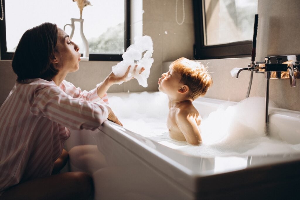 Mother washing little son in bathroom
