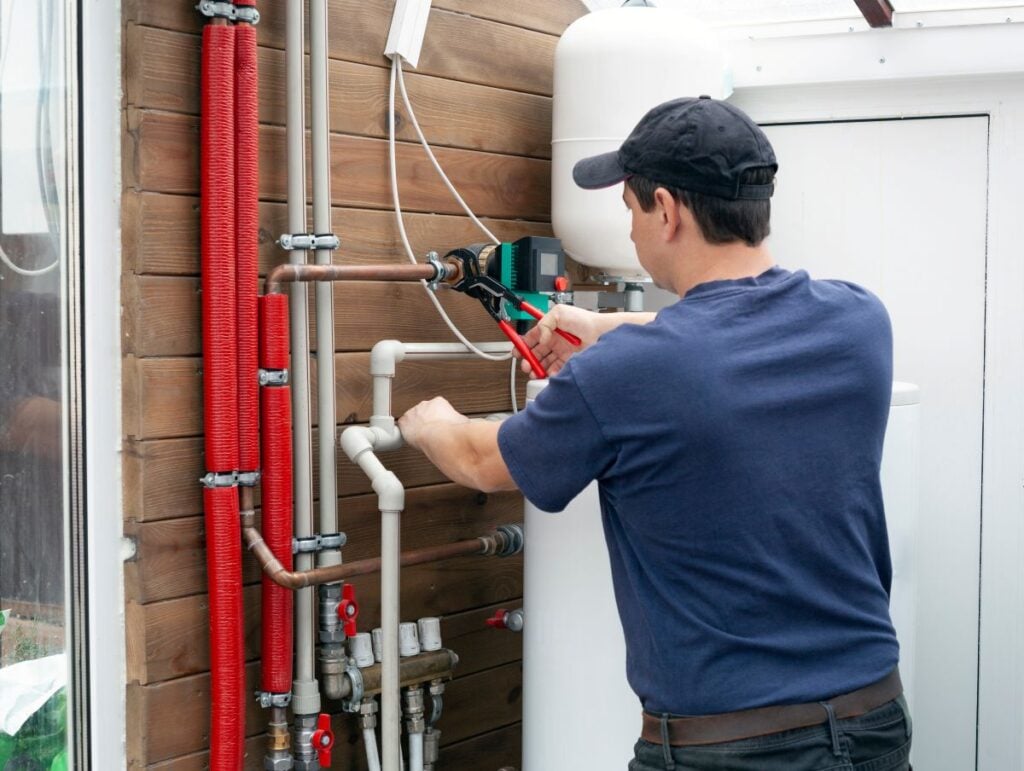 boiler vs furnace worker using wrench to repair pipes