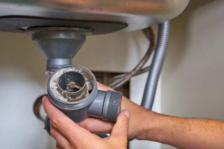 drain cleaning worker hand holding piece of pipe dirty