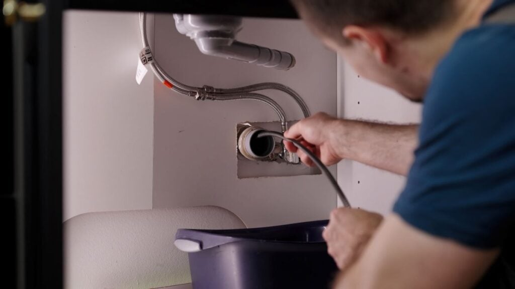 drain cleaning worker unclogging pipe