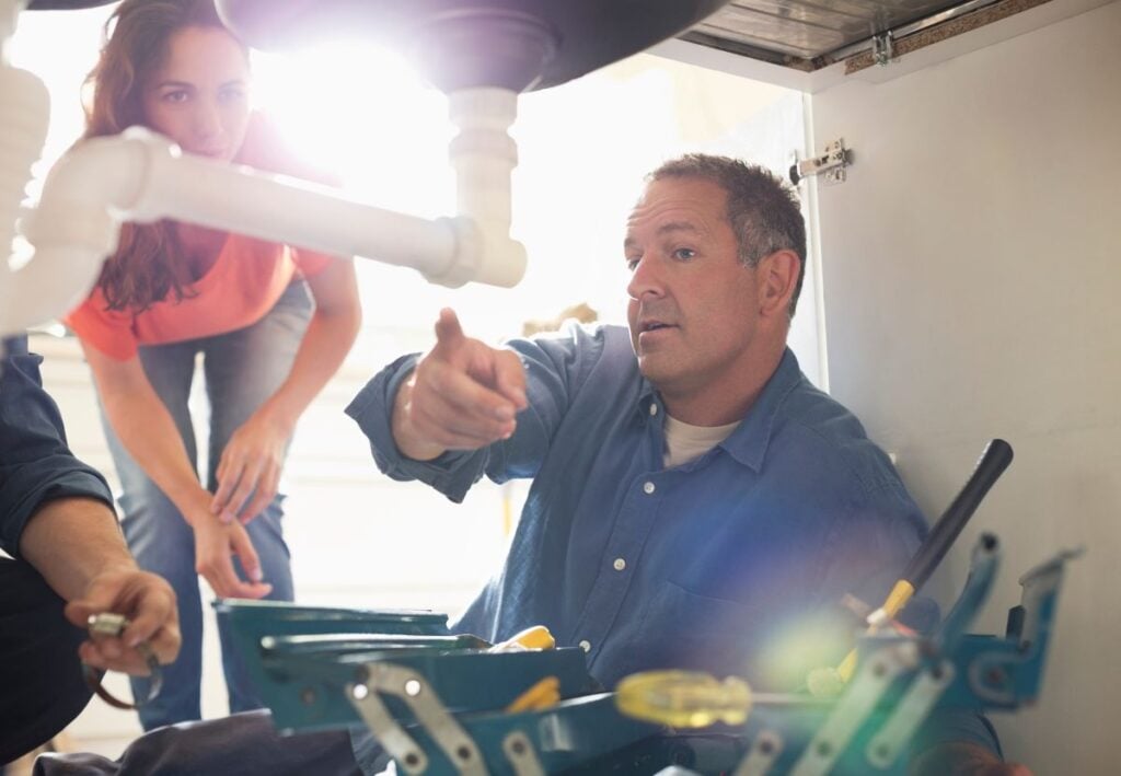 kitchen sink plumbing plumber showing woman a problem