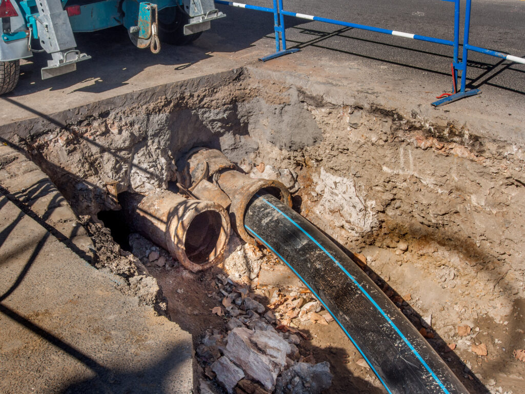 New plastic sewer pipe being inserted into a broken cast iron pipe.
