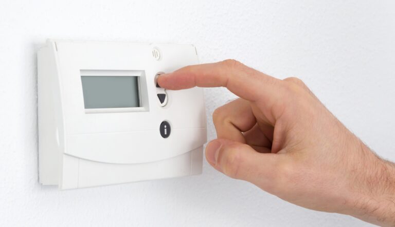 Vintage digital thermostat hanging on a white wall - Man adjusting