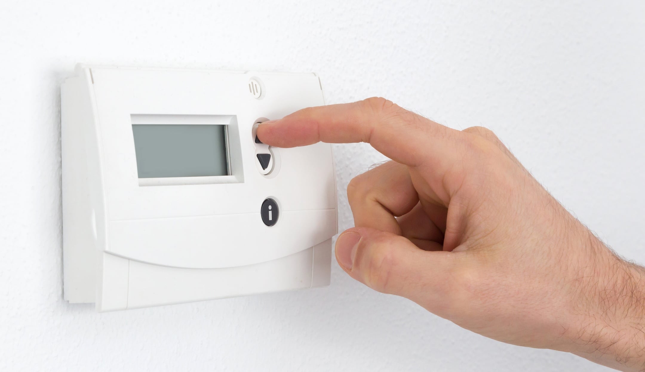 Vintage digital thermostat hanging on a white wall - Man adjusting