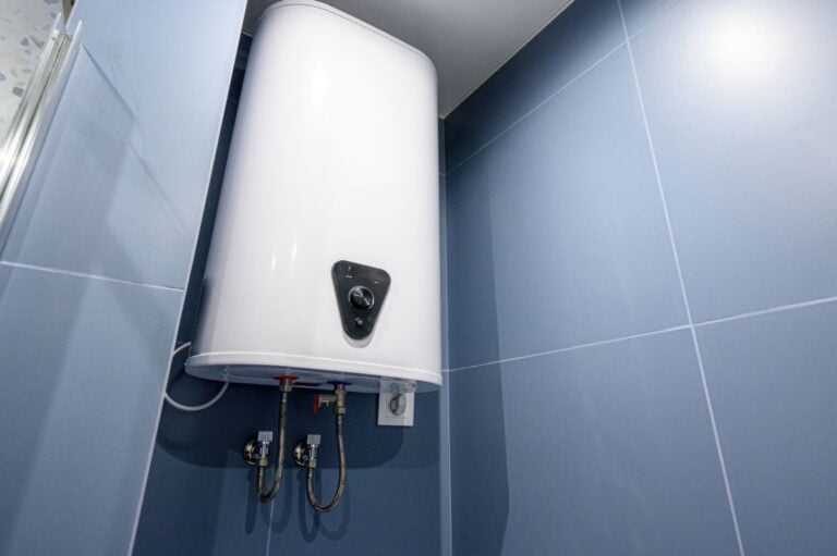 White electric water heater mounted on blue tiled wall in bathroom