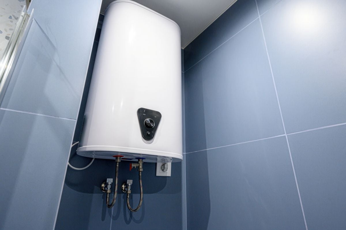 White electric water heater mounted on blue tiled wall in bathroom