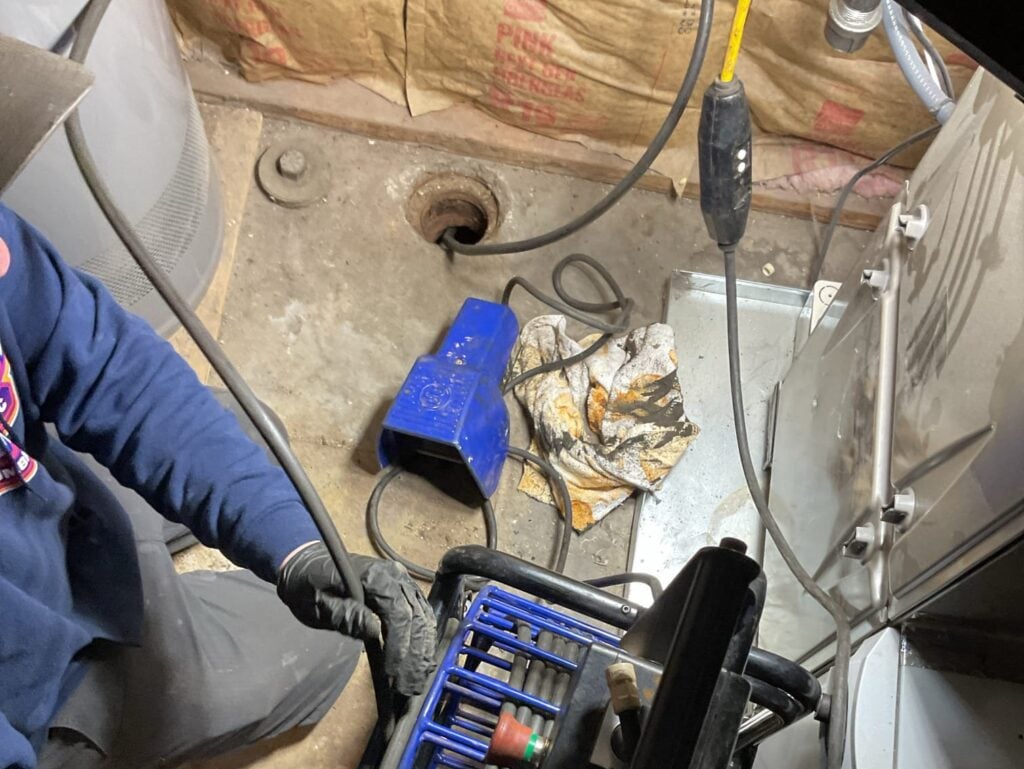 sump pump repair worker inside room cleaning sump pump