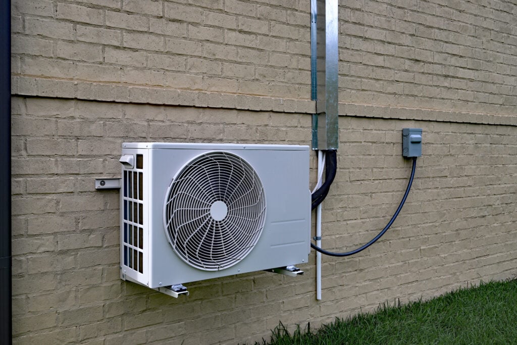 mini split heat pump Air Conditioner mini split system next to home with painted brick wall and space for text copy