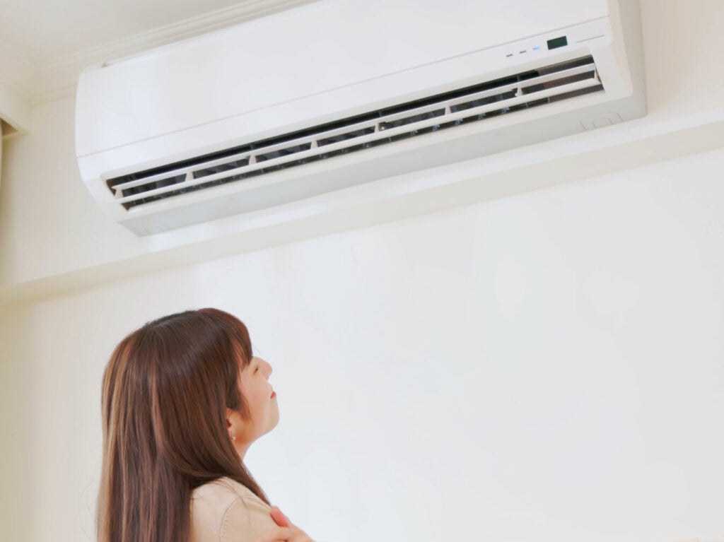 emergency ac repair asian woman turn on heater and feel warm in winter standing at home