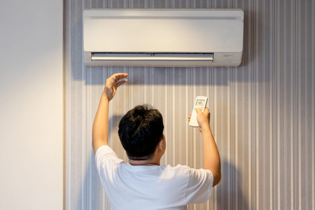 ac compressor Asian man having a problem with air conditioner is not producing cold air,air conditioning only wind out,refrigerant leaking,dirt and clogging in air filter or malfunctions of the evaporator coil unit