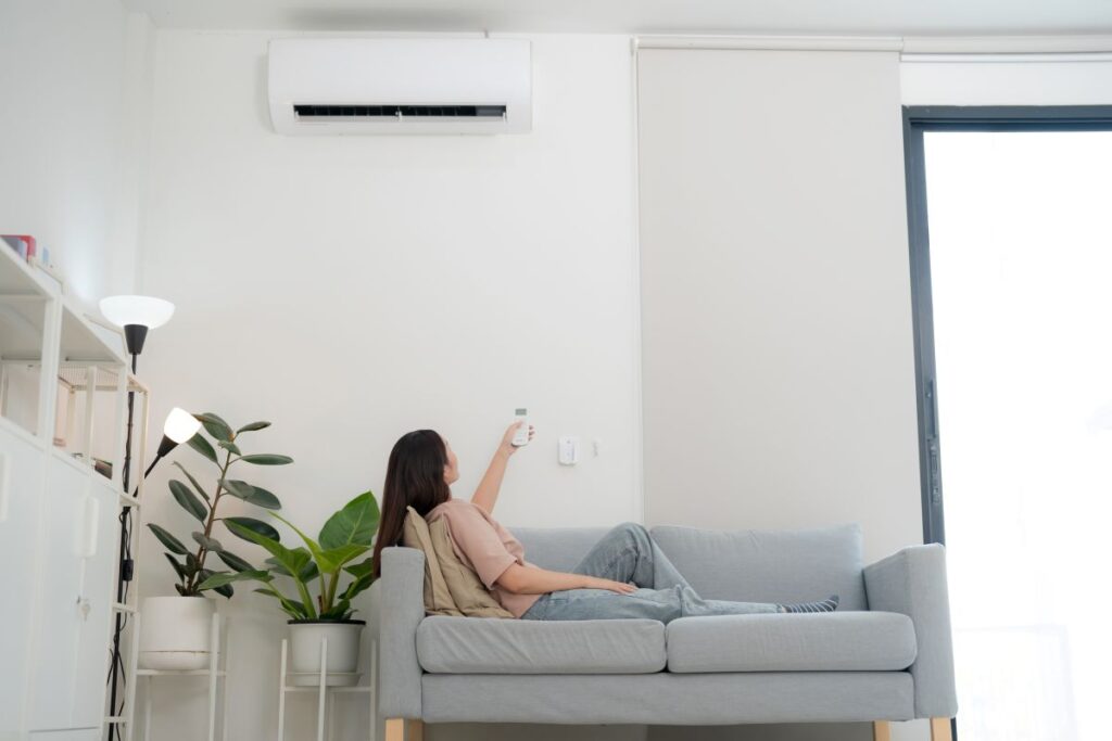 ac blowing warm air woman using controller to turn on unit
